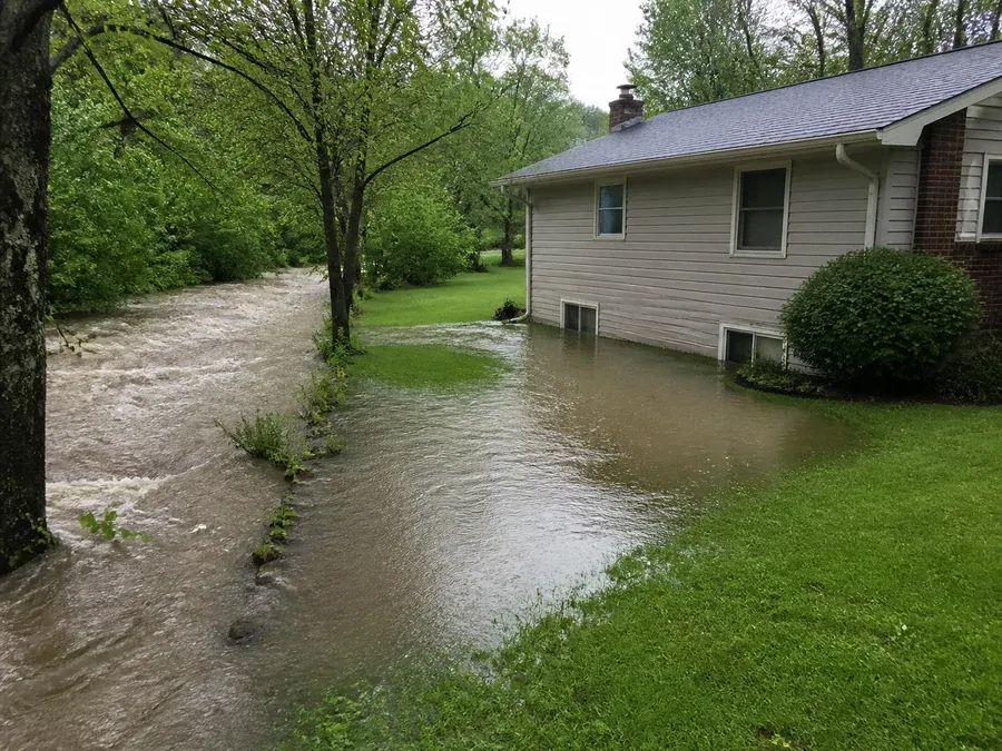 An overflowing creek spreading across a normally dry yard toward a North Carolina home